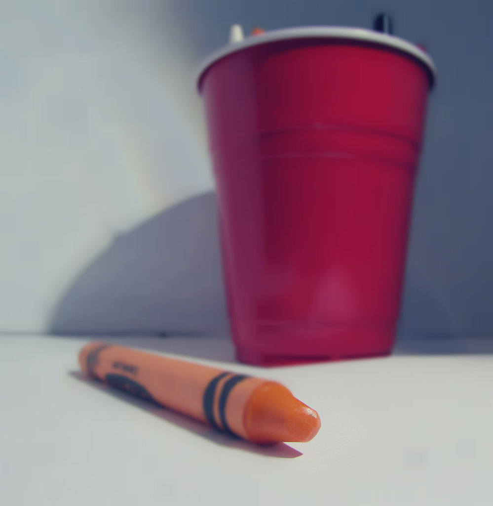 Orange crayon outside of cup